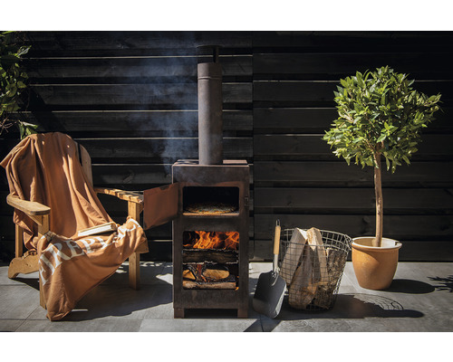 Scene met pizzaoven, hout, schep en stoel met deken in de tuin