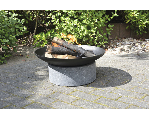 Vuurplaats van staal en beton met brandend hout in de tuin