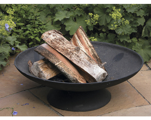 Gietijzeren vuurschaal met houtblokken in de tuin