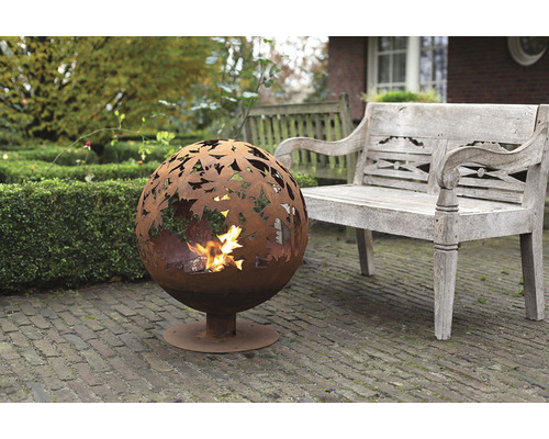 Metalen vuurkorf in bolvorm met bladmotief in de tuin