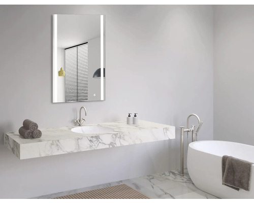 Moderne badkamer met verlichte spiegel, wastafel met marmeren blad en bad.