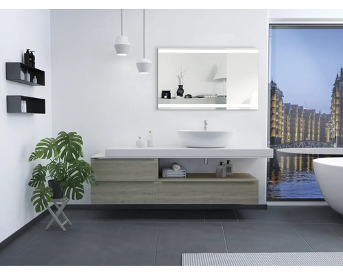 Lichte badkamer met wastafel, spiegel, bad en raam met uitzicht op de stad