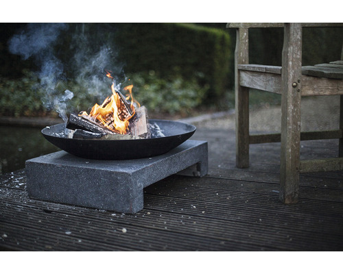 Vuurplaats met brandend hout op stenen voet in de tuin