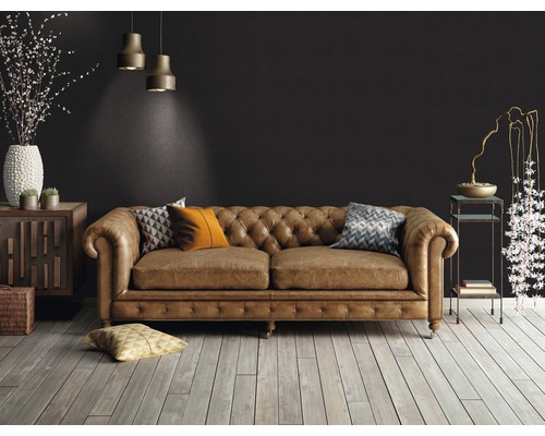 Woonkamer met bruine leren bank in Chesterfieldstijl, houten vloer en decoratieve elementen