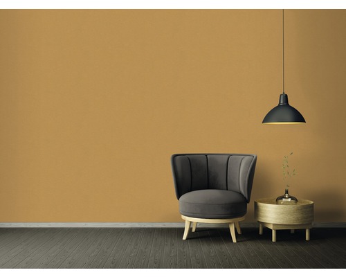 Woonkamer met fauteuil, bijzettafel en hanglamp voor een effen muur