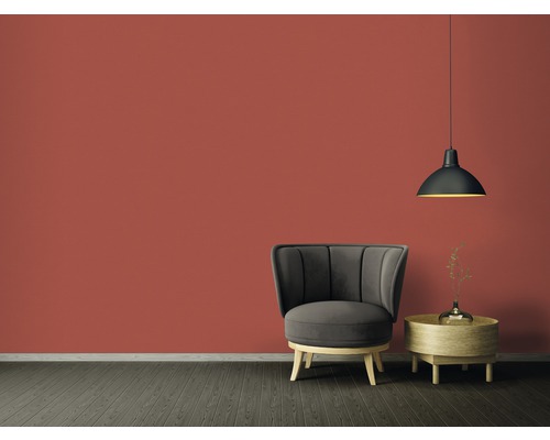 Woonkamer met fauteuil, bijzettafel en hanglamp voor een gekleurde muur