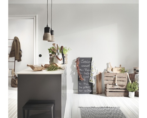 Lichte keukenruimte met kookeiland, kruk, verlichting, schoolbord en decoratieve keukenspullen.