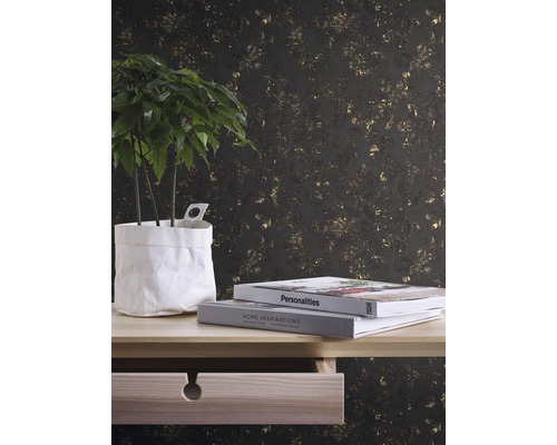 Decoratief behang met plantenmotief achter een tafel met potplant en boeken