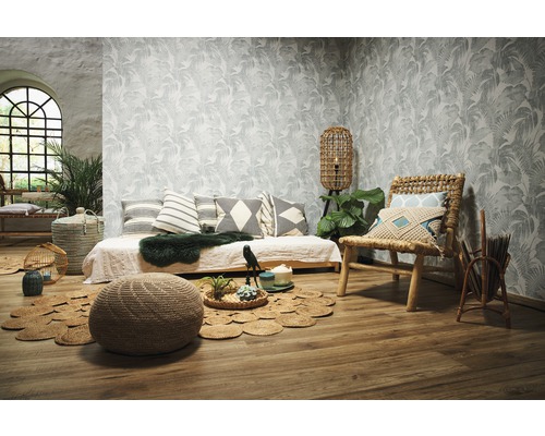 Woonkamer met daybed, rotan stoel, poef en behang met motief