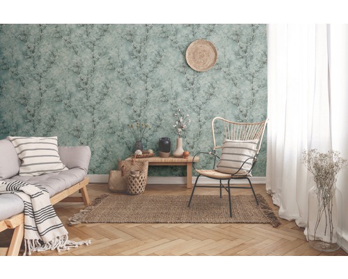 Woonkamer met patroonbehang, bank, stoel en decoraties voor een gezellige sfeer.
