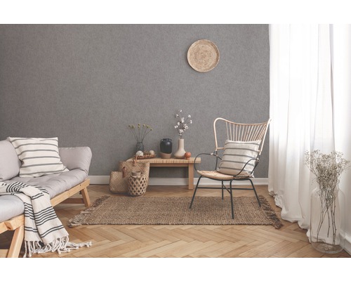 Lichte woonkamer met bank, stoel, vloerkleed en grijs behang