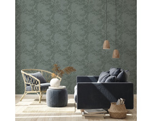 Woonkamer met bloemmotief behang, fauteuil, bank en bijzettafel.