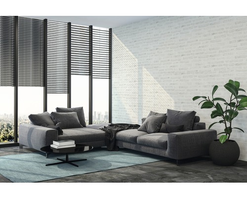 Woonkamer met grijze hoekbank, rolluiken voor het raam en kamerplant