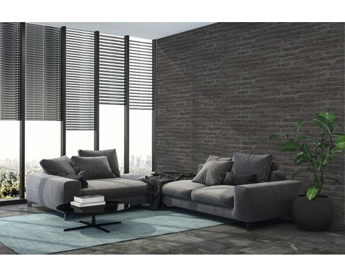 Woonkamer met hoekbank, jaloezieën en bakstenen muur