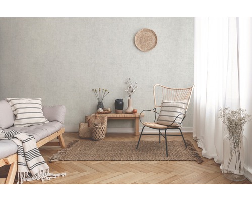 Woonkamer met bank, stoel en tapijt op parketvloer voor een gestructureerde wand