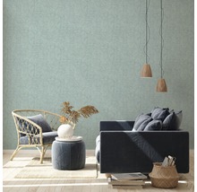 Licht, gestructureerd behang in een woonkamer met fauteuil, bank en decoraties.