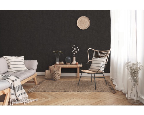 Woonkamer met donkere muur, bank, fauteuil, houten tafel en vloerkleed