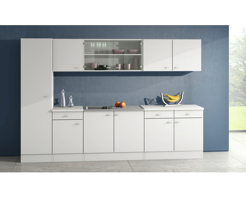 Lichte keuken met witte kasten en werkbladen tegen een blauwe muur.