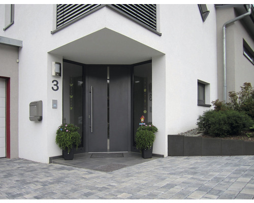 Entree van een huis met grijze voordeur, huisnummer en plantenbakken