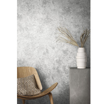 Scene met houten stoel, kussen, vaas en decoratieve takken voor een grijze muur