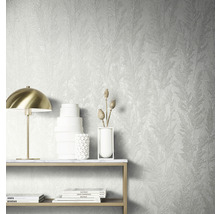 Wanddecoratie met gestructureerd behang met plantenmotief, tafel met decoratie en lamp