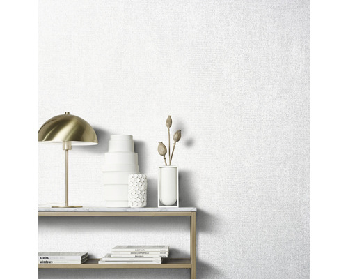 Licht behang met stofstructuur in de woonkamer met tafel en decoraties.