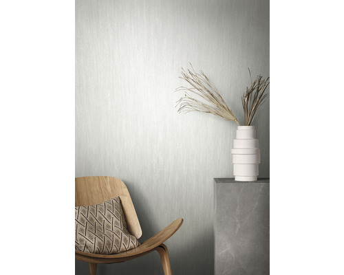 Scene met een licht vliesbehang, een houten stoel met kussen en een vaas met decoratie op een sokkel
