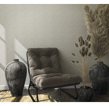 Woonkamer met patroonbehang, fauteuil en decoratie in vazen.