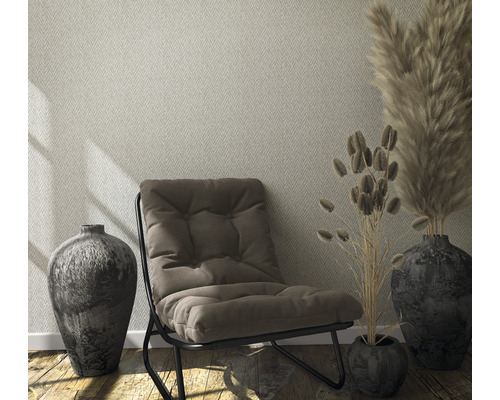 Woonkamer met patroonbehang, fauteuil en decoratie in vazen.