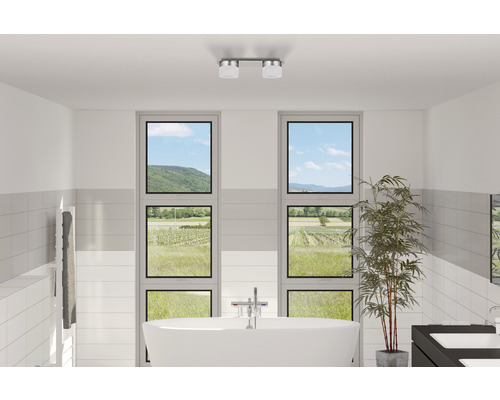 Lichte badkamer met vrijstaand bad, handdoekradiator, twee ramen met uitzicht op het landschap en plafondlamp
