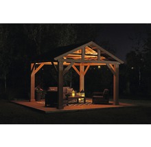 Verlichte paviljoen met tuinmeubelen op houten terras ''s nachts.