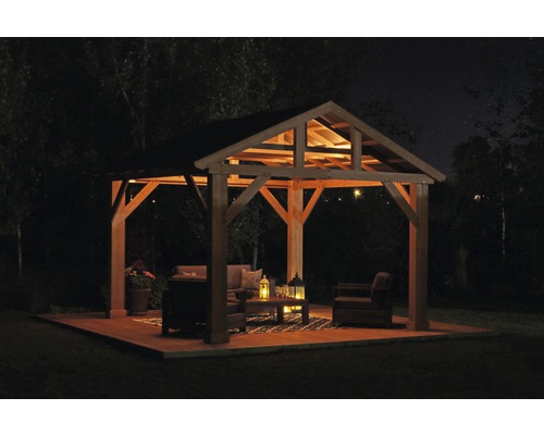 Verlichte paviljoen met tuinmeubelen op houten terras ''s nachts.