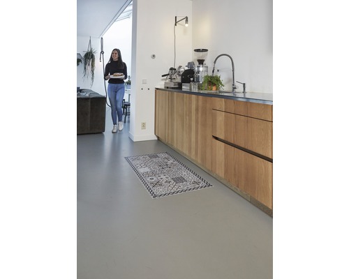 Lichte kamer met kitchenette en een vrouw met een bord en een tapijt op de vloer.