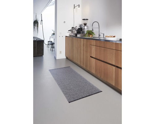 Grijs vloerkleed in een keuken met houten kasten.