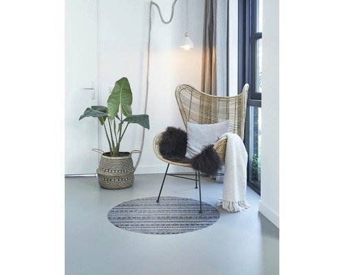 Lichte kameropstelling met rotan stoel, kamerplant, rond vloerkleed en decoratie