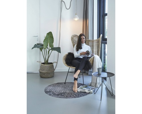 Lichte interieur met rotan stoel, plant, tapijt en lezende vrouw