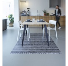 Eetkamer met houten tafel, witte stoelen en een tapijt met motief
