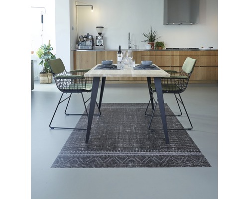 Eetkamer met tafel, stoelen en vloerkleed in een lichte ruimte.