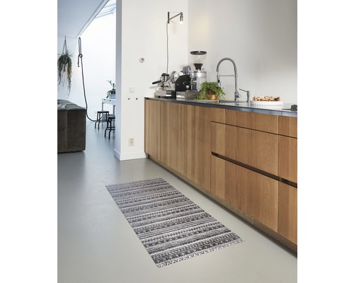 Keuken met houten kasten en een gestreept vloerkleed