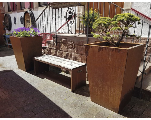 Buitenruimte met plantenbakken, bloemen en een bank