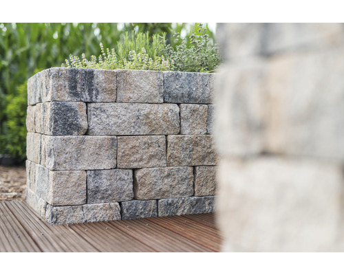 Steunmuur van stenen blokken met planten erop op houten terras