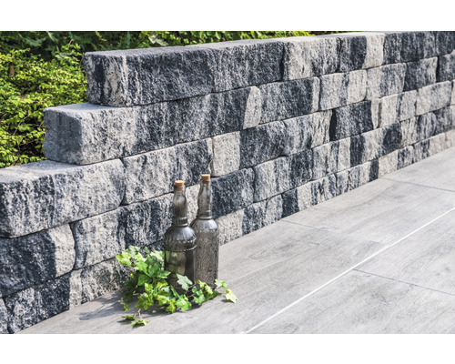 Steunmuur van betonstenen met decoratieve flessen en planten op vloerplaten