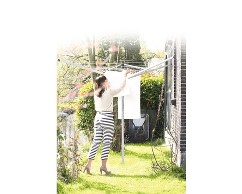 Vrouw hangt was op aan een wasmolen in de tuin