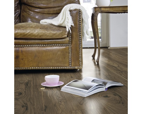 Woonkamer met laminaatvloer in houtlook, fauteuil, tafel en boek
