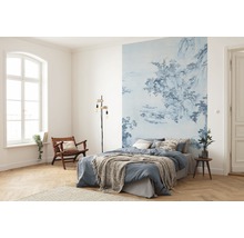 Slaapkamer met blauw gedessineerd fotobehang, bed, leeslamp en houten stoel