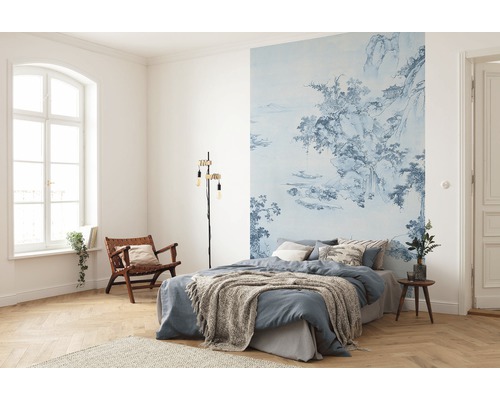 Slaapkamer met blauw gedessineerd fotobehang, bed, leeslamp en houten stoel