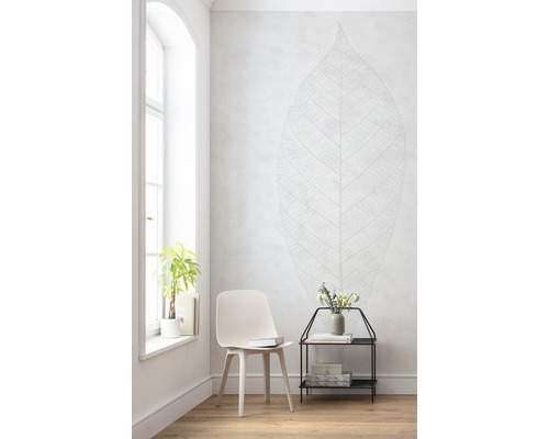 Lichte kamer met stoel, bijzettafel, plant en muursticker met bladdesign