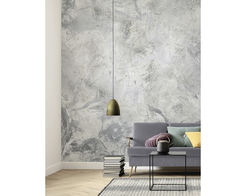 Woonkamer met patroonbehang, hanglamp, bank, tafel en vloerkleed