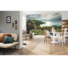 Woonkamer met fotobehang van een tropisch eiland, een bank, een tafel en stoelen.