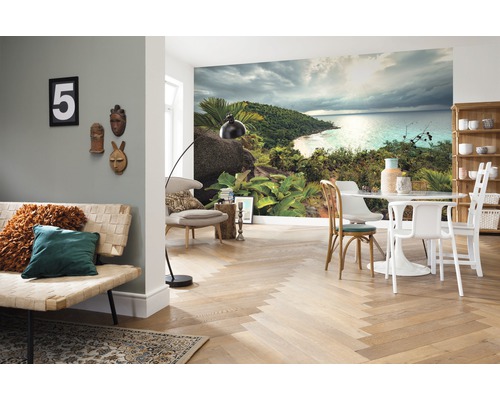 Woonkamer met fotobehang van een tropisch eiland, een bank, een tafel en stoelen.